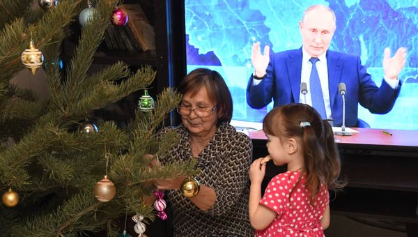 Корнакова Людмила Павловна и ее внучка Ева наряжают елку и смотрят трансляцию ежегодной большой пресс-конференции президента РФ Владимира Путина у себя дома в селе Смоленка Читинского района Забайкальского края