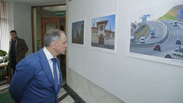 Владимир Константинов рассматривает выставку РИА Новости Крым к семилетию Крымской весны
