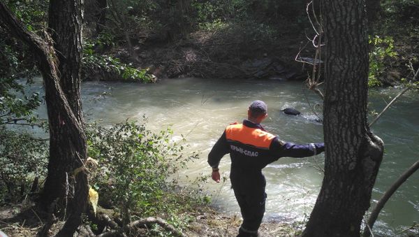 Спасатель возле лежащего на дне реки автомобиля