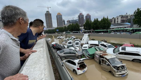 21 июля 2021 года. Люди смотрят на машины, утонувшие в паводковых водах после проливных дождей в городе Чжэнчжоу в центральной провинции Хэнань Китая