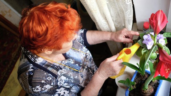Женщина поливает комнатные растения