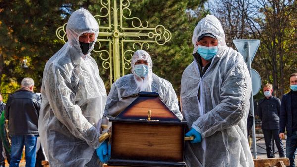 По ковидным правилам, умерших от коронавируса хоронят в закрытых гробах, сотрудники ритуального предприятия одеты в СИЗы.