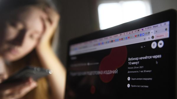 Девушка со смартфоном возле ноутбука