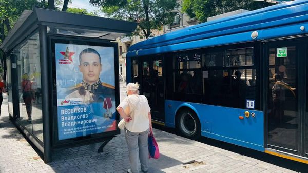 Женщина рассматривает фото героя спецоперации Владислава Веселкова на остановке в Севастополе