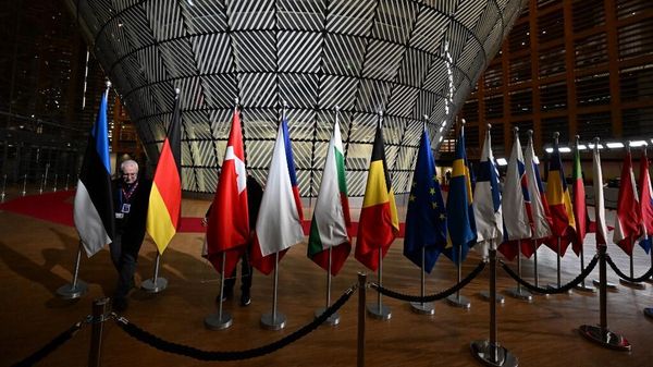 Рабочий вывешивает флаги европейских стран перед прибытием европейских лидеров на саммит ЕС-Западные Балканы в европейской штаб-квартире в Брюсселе