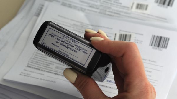 Врач клинико-диагностической лаборатории ставит печать с результатом пцр-исследования