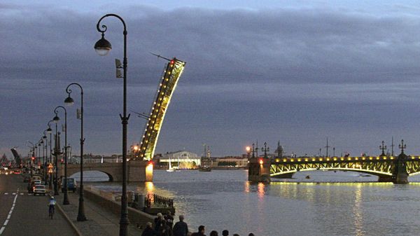 Жители и гости Санкт-Петербурга во время ночной прогулки по набережной наблюдают, как разводится Троицкий мост