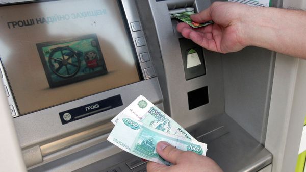 Житель Симферополя снимает наличные деньги через банкомат. Архивное фото