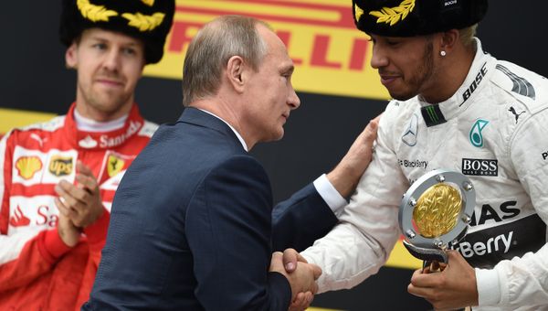 Президент России Владимир Путин (в центре) вручает Кубок Гран-при России гонщику команды Мерседес Льюису Хэмилтону (справа)