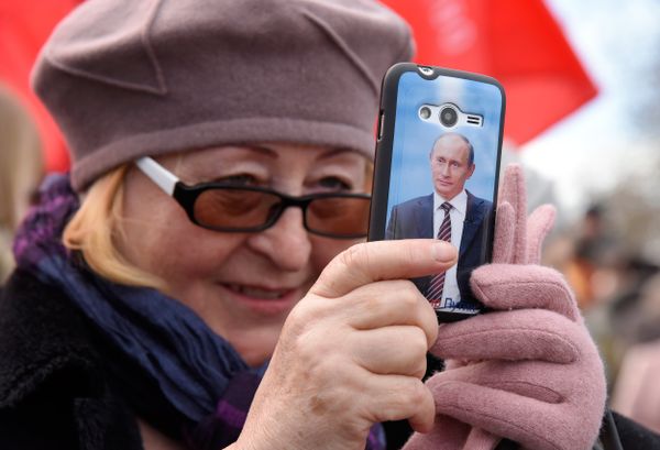 Севастополь. Женщина снимает на телефон с изображением Владимира Путина Севастополь. Женщина снимает на телефон с изображением Владимира Путина