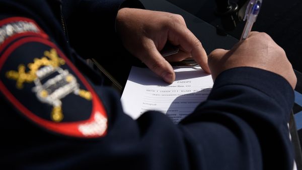 Сотрудник мобильного поста ДПС ГИБДД оформляет предупреждение о необходимости замены украинских номеров в течение 10 дней