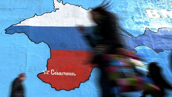 Прохожие у нарисованной на стене карты Крыма в цветах российского флага в Москве Прохожие у нарисованной на стене карты Крыма в цветах российского флага в Москве