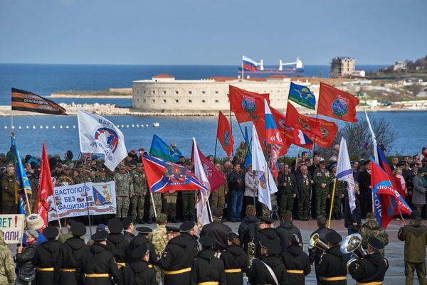 Участники митинга в честь третьей годовщины воссоединения Крыма с Россией на мысе Хрустальный в Севастополе. На дальнем плане - Севастопольская крепость