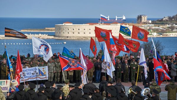 Участники митинга в честь третьей годовщины воссоединения Крыма с Россией на мысе Хрустальный в Севастополе. На дальнем плане - Севастопольская крепость