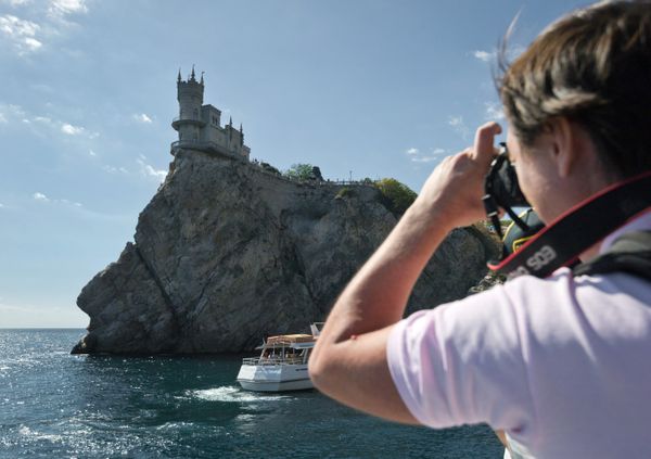 Турист фотографирует замок Ласточкино гнездо