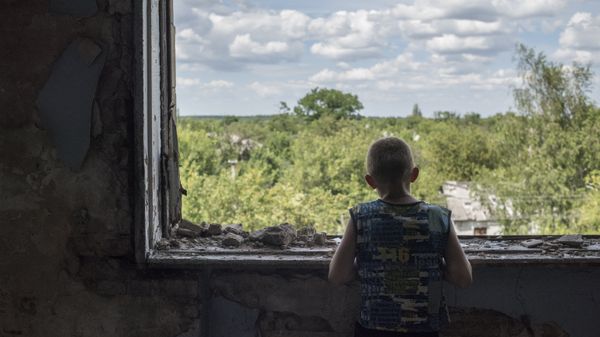 Подросток у окна в разрушенном спортивном зале средней школы в Горловке. Архивное фото