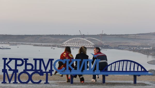 Люди на скамейке Крымский мост наблюдают за морской операцией установки железнодорожной арки моста через Керченский пролив Люди на скамейке Крымский мост наблюдают за морской операцией установки железнодорожной арки моста через Керченский пролив