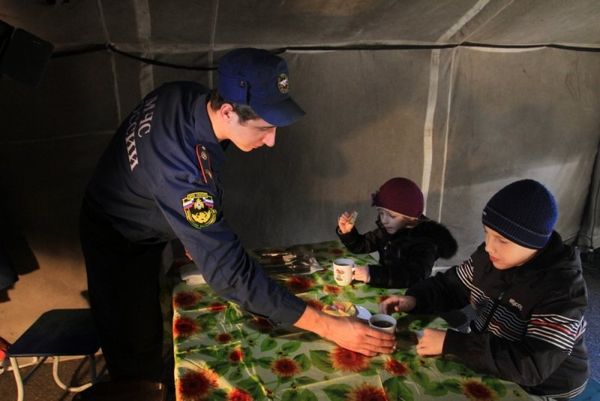 Сотрудник МЧС поит чаем детей в пункте обогрева