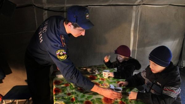 Сотрудник МЧС поит чаем детей в пункте обогрева