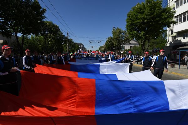 Участники Первомайского шествия несут большой флаг России Участники Первомайского шествия несут большой флаг России