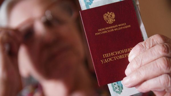 Женщина держит пенсионное удостоверение и денежные купюры