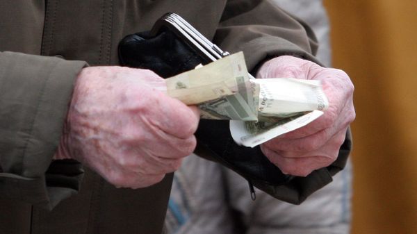 Пенсионер держит в руках кошелек и деньги