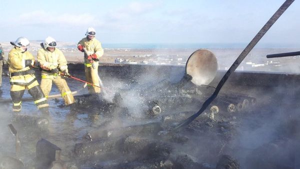 Сотрудники МЧС тушат пожар на месте взрыва газовых баллонов на крыше девятиэтажного дома в Щелкино