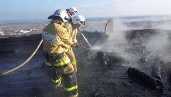 Сотрудники МЧС тушат пожар на месте взрыва газовых баллонов на крыше девятиэтажного дома в Щелкино