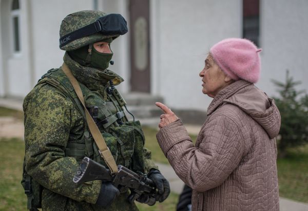 Местная жительница разговаривает с военнослужащим в селе Перевальное недалеко от Симферополя.