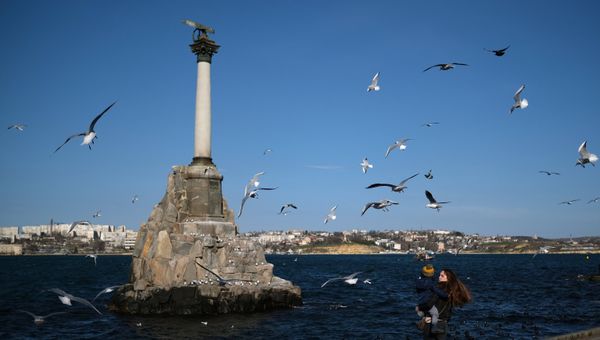 Девушка с ребенком стоят возле памятника затопленным кораблям в Севастополе