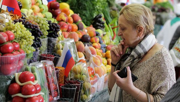 Женщина у прилавка с овощами и фруктами
