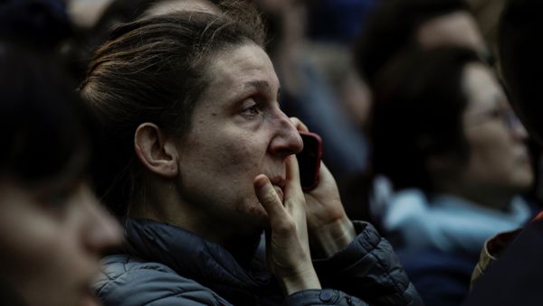 Женщина смотрит на горящий собор Парижской Богоматери