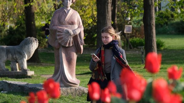 Девушка смотрит в мобильный телефон на Крымской набережной в парке искусств Музеон в Москве.