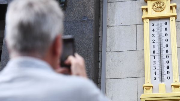 Мужчина фотографирует термометр 
