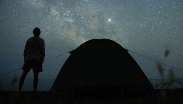 Мужчина наблюдает за звездным небом на берегу Черного моря возле поселка Морское в Крыму Мужчина наблюдает за звездным небом на берегу Черного моря возле поселка Морское в Крыму