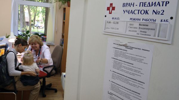 Молодая женщина с ребенком на приме у врача-педиатра. Архивное фото