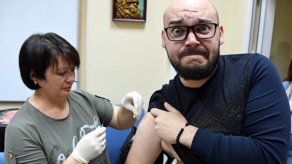 Медик делает прививку с вакциной против гриппа Медик делает прививку с вакциной против гриппа