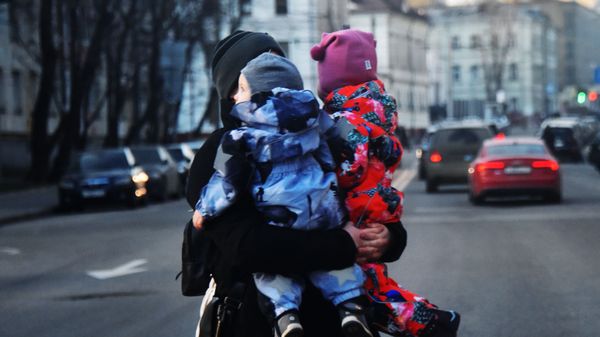 Женщина с двумя детьми на руках переходит дорогу. Женщина с двумя детьми на руках переходит дорогу.