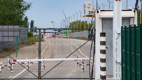 Дорога от одного пункта пропуска до другого огорожена высоким серым забором, который российские